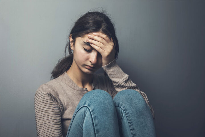 Girl in crisis sitting with hand on forehead