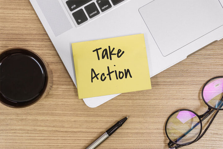 take action yellow sticky note on laptop